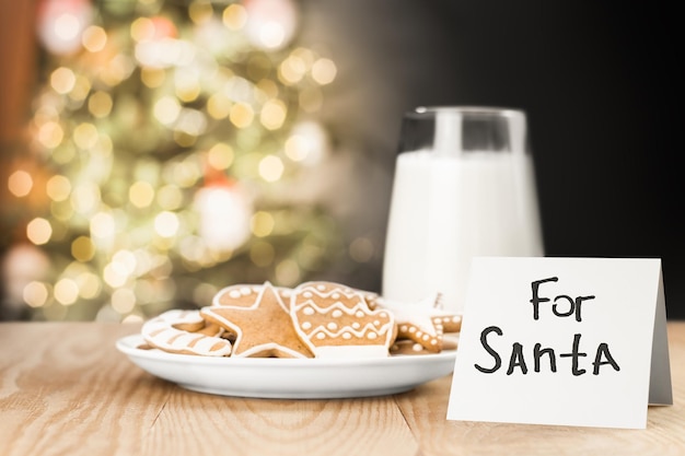 Biscuits au lait et une note pour le Père Noël sur la table sur fond de sapin de Noël