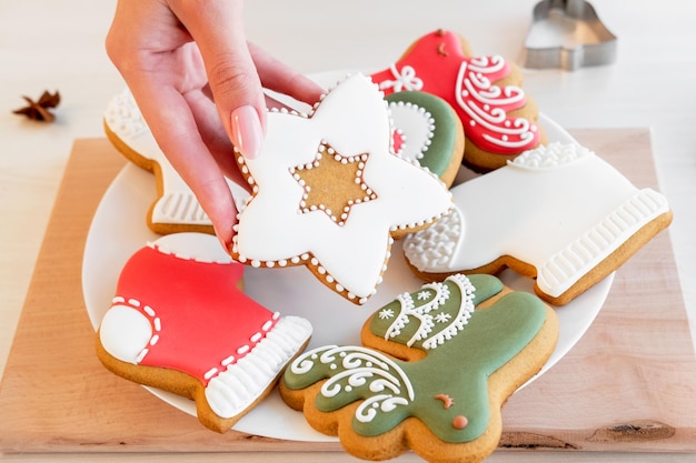 Biscuits au pain d'épice traditionnels culinaires festifs méconnaissables main féminine tenant une pâte à glacer