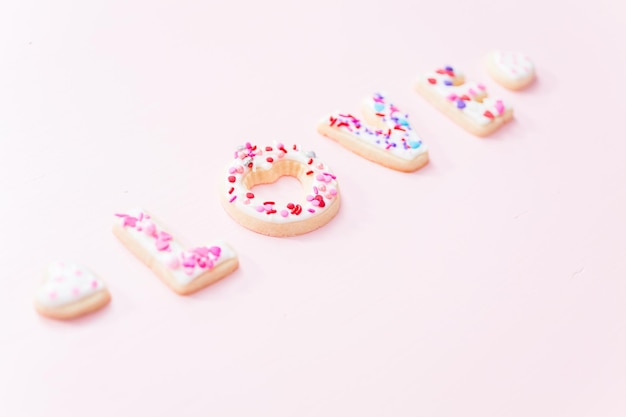 Biscuits au sucre décorés de glaçage royal pour la Saint-Valentin sur fond rose.