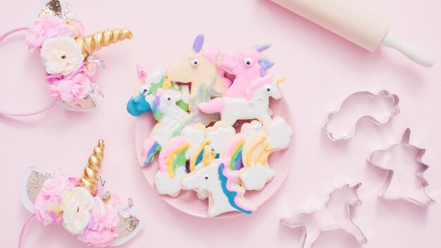 Biscuits au sucre en forme de licorne décorés de glaçage royal sur plaque rose.