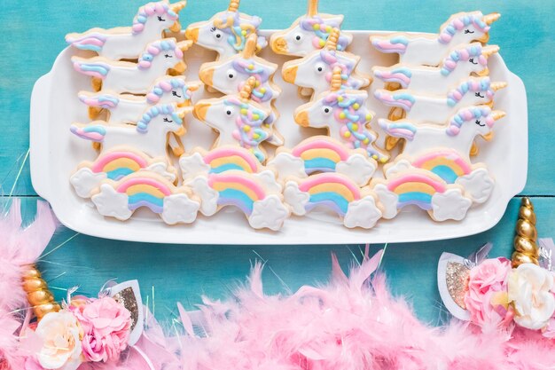 Biscuits au sucre de licorne décorés de glaçage royal sur fond bleu.