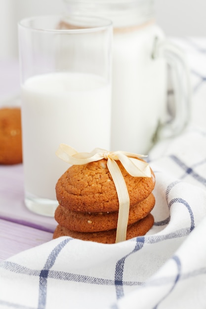 Biscuits au verre de lait et biscuit avec torchon de cuisine sur fond clair