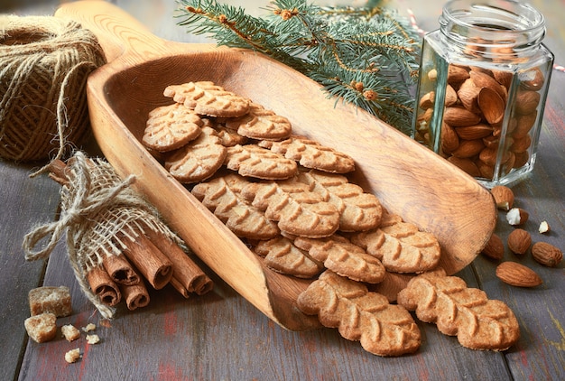 Biscuits aux amandes dans une pelle en bois larde avec noix d'amande, sucre et cannelle