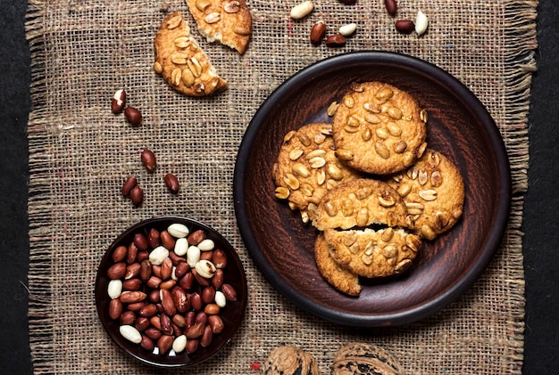 Biscuits aux arachides faits maison sur une plaque brune avec des arachides crues en surface Nourriture de style rustique Vue de dessus à plat