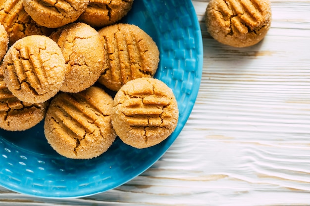 Biscuits aux arachides en plaque bleue sur fond de bois blanc