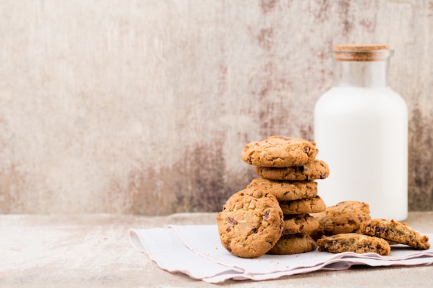 Biscuits aux pépites d'avoine au chocolat avec du lait sur la table en bois rustique.