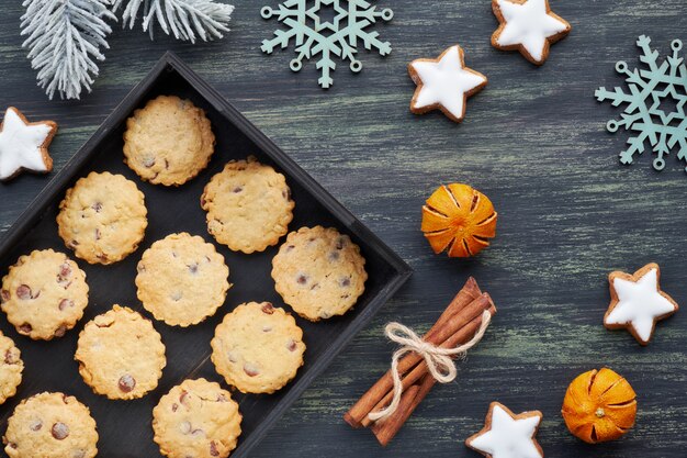 Biscuits aux pépites de chocolat de Noël, plat avec des épices et des décorations d'hiver sur dark