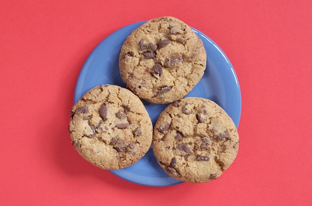 Biscuits Aux Pépites De Chocolat Sur Une Plaque Bleue Sur Fond Rouge