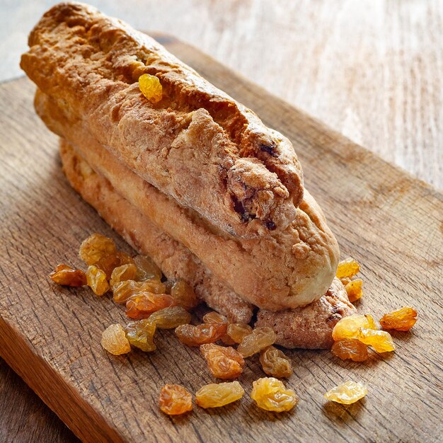 Biscuits aux raisins et raisins secs roulés sur une planche de bois.