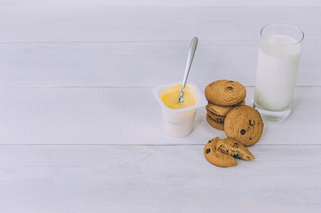 Biscuits à l'avoine avec du chocolat sur un espace lumineux avec un verre de lait et de yaourt.