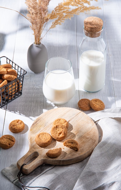 Biscuits à L'avoine Frais Faits Maison Sur Une Planche à Découper En Bois Avec Un Verre De Lait Végétalien Sur Une Table En Bois Blanc