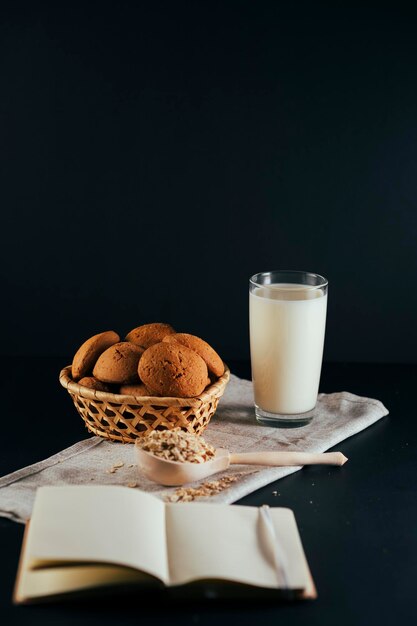 Biscuits à l'avoine avec un verre de lait sur une serviette sur fond noir Le concept d'un petit-déjeuner sain