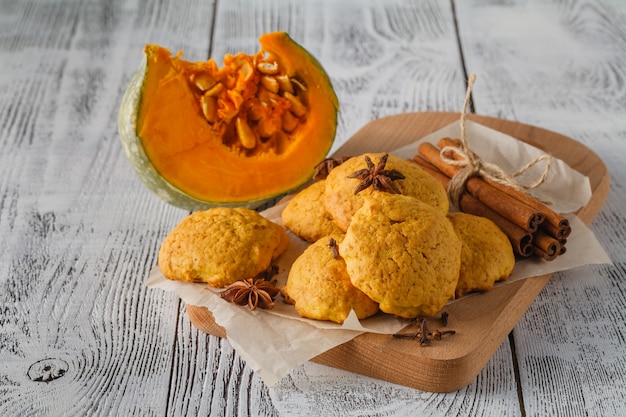 Biscuits à la citrouille sur table en bois avec citrouilles sur fond