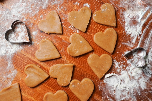 Biscuits coeur pâte et moules sur table avec de la farine célébration de la Saint-Valentin cuisson à la maison
