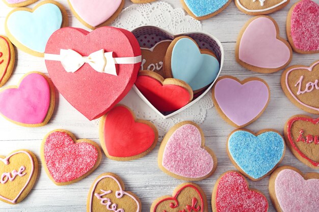 Biscuits colorés de coeur de Valentine avec la boîte actuelle sur le plan rapproché de table en bois