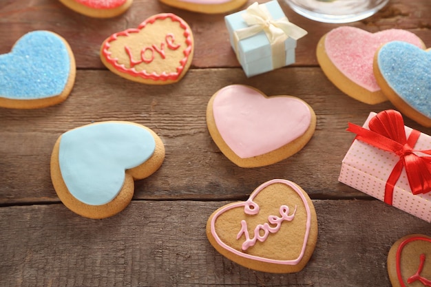 Biscuits colorés de coeur de Valentine avec des boîtes présentes sur le fond en bois