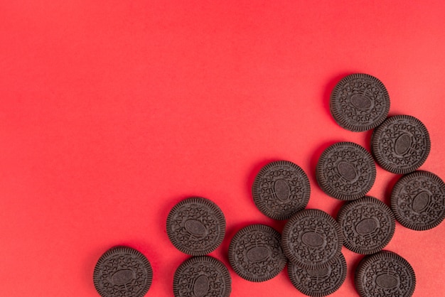 Biscuits et crème de vanille en morceaux empilés en groupe sur fond rouge pour christm