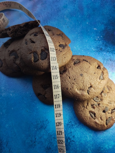 biscuits croustillants aux pépites de chocolat et ruban à mesurer la perte de poids sur fond bleu