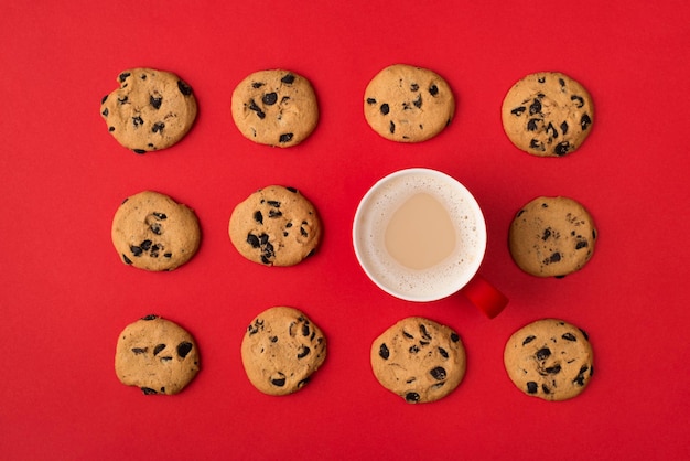 Biscuits délicieux avec une tasse de café aromatique frais debout dans des rangées de plats isolés cadre de fond rouge de couleur vive
