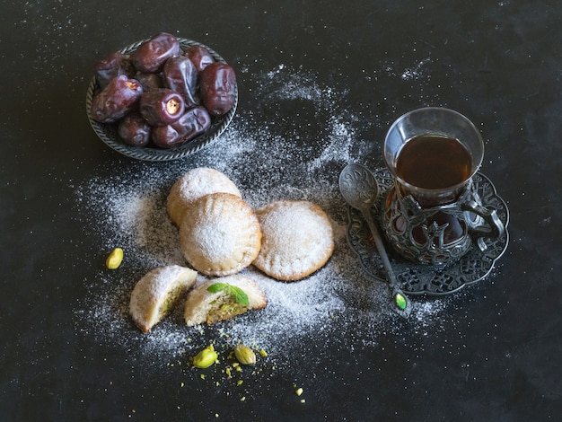 Biscuits égyptiens "Kahk El Eid" avec dattes et tasse de thé servis dans un tableau noir. Cookies de la fête islamique El Fitr.