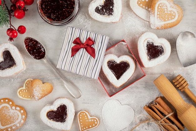 Biscuits faits maison avec de la confiture de framboises sur une table en bois blanc pour Noël ou la Saint-Valentin.