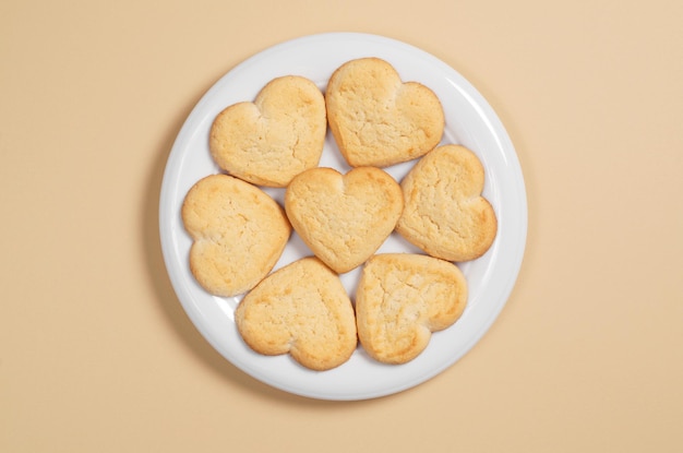 Biscuits faits maison en forme de coeur dans une assiette sur une vue de dessus de fond marron clair