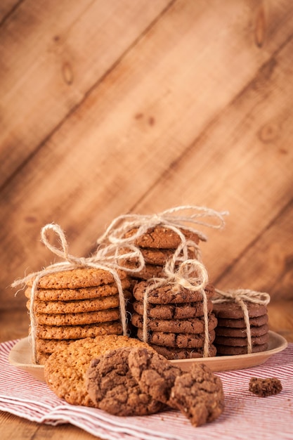 Biscuits faits maison à grains entiers avec flocons d'avoine, lin et graines de sésame et biscuits traditionnels aux pépites de chocolat sur une table en bois rustique foncé.