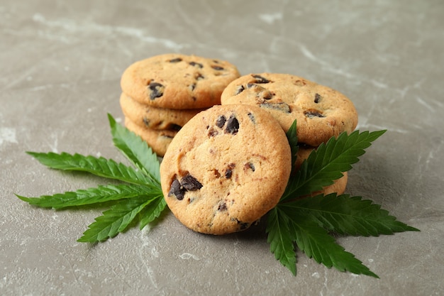 Biscuits et feuilles de cannabis sur une table texturée grise