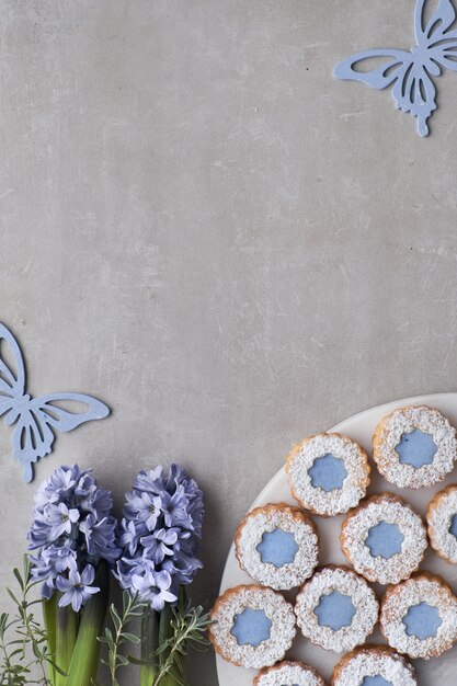 Biscuits Flower Linzer avec vitrage bleu sur béton léger décoré de fleurs et de papillons en jacinthe bleue