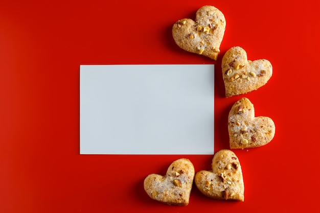 Biscuits sur fond rouge et carte de vœux vierge Carte de vœux vide et biscuits en forme de cœur