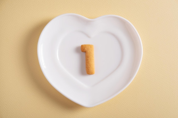 Biscuits formant le numéro 1 sur la plaque blanche et le fond clair jaune