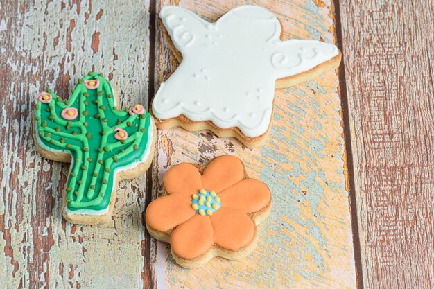 Biscuits en forme d'ange, fleur et cactus sur la table en bois.