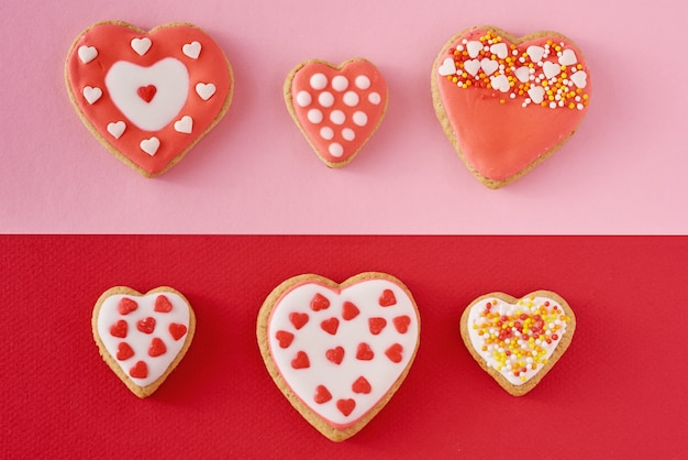 Biscuits en forme de coeur décoré sur une surface de couleur rouge et rose, vue de dessus