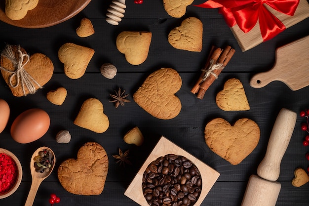 Biscuits en forme de coeur en pain d'épice, épices, grains de café et fournitures de pâtisserie.