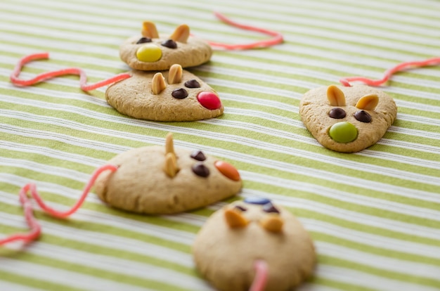 Biscuits en forme de souris et queue de réglisse rouge sur nappe à rayures vertes