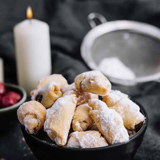 Biscuits frais faits maison saupoudrés de sucre en poudre dans un bol noir