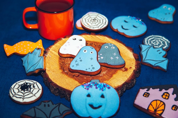 Biscuits d'Halloween en pain d'épice peints et une tasse orange sur fond bleu