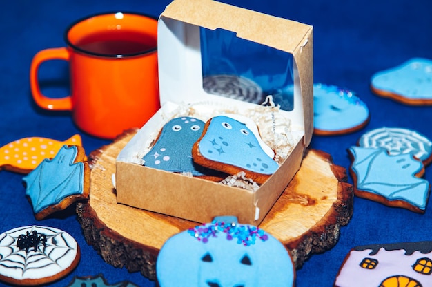 Biscuits d'Halloween en pain d'épice peints et une tasse orange sur fond bleu