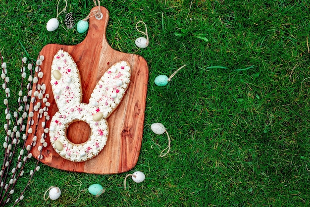 Biscuits de lapin de Pâques sur une planche de bois avec des oeufs de pâques sur l'herbe