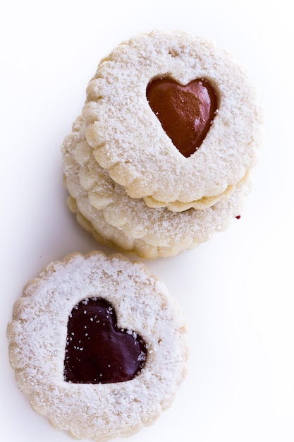 Biscuits Linzer Torte sur fond blanc avec du sucre en poudre saupoudré sur le dessus.