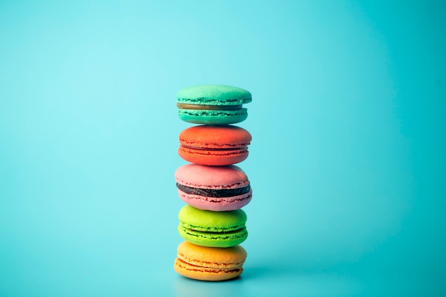 Biscuits macarons colorés (macarons) sur fond bleu. Pâtisseries festives lumineuses, desserts et bonbons. Fond de cuisson