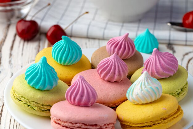 Biscuits macarons français de couleurs vives servis dans une assiette en céramique blanche