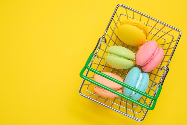 Biscuits macarons français dans le panier sur fond jaune