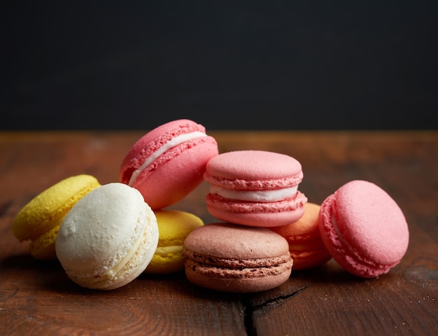 Biscuits macarons multicolores au four se trouvent dans une rangée sur un fond en bois brun, Close up