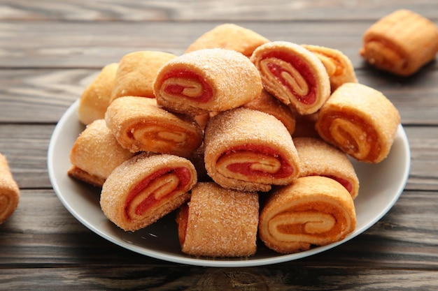 Biscuits maison, mini rouleaux à la confiture d'abricot en assiette sur fond marron. Vue de dessus