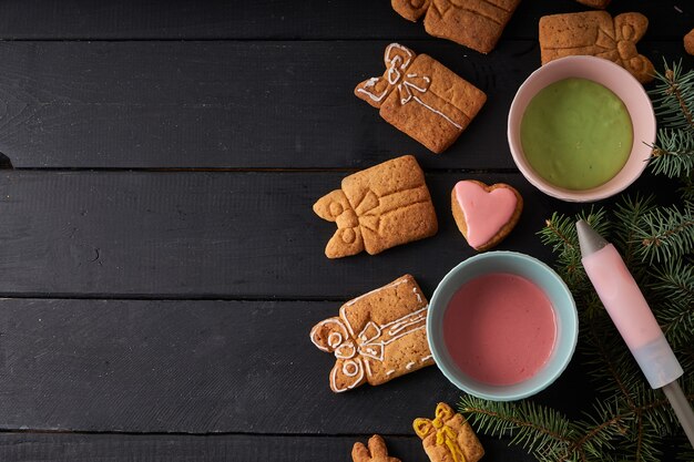 Biscuits maison savoureux avec glaçage sur table sombre avec branche de sapin. Concept de Noël et d'hiver Close up