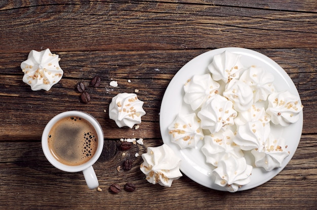 Biscuits de meringue aux noix et tasse de café sur fond de bois foncé, vue de dessus