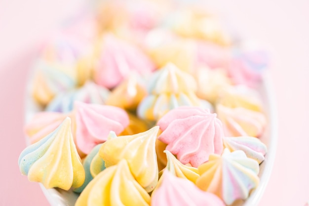 Biscuits de meringue licorne multicolores sur une assiette de service blanche.