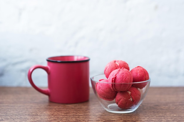 Biscuits multicolores sous forme de noix avec crème fourrée et tasse de café sur une table en bois Biscuits faits maison Copier l'espace Bonbons savoureux