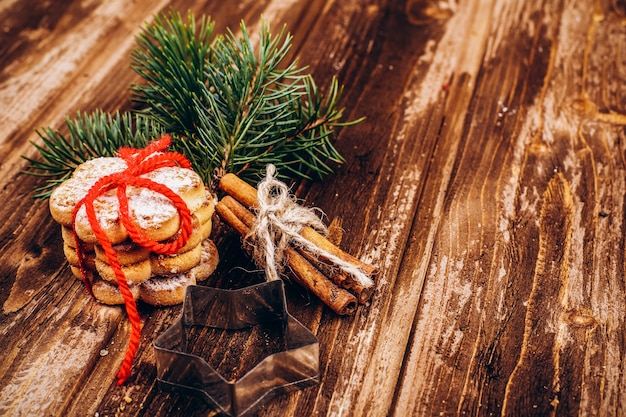 Biscuits de Noël, cannelle et branche de sapin sur une table en bois